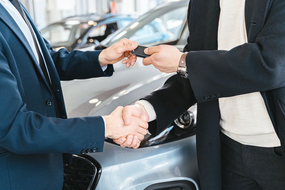A car key being handed over with a handshake